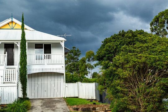 Storm clouds behind white Queenslander style house.