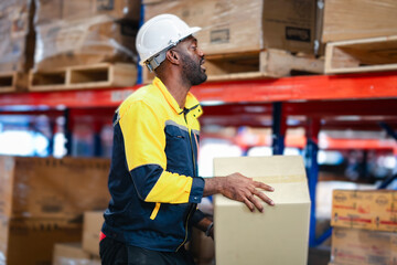 Warehouse worker lifts a brown box and places it on a storage shelf. He is doing manual labor and...