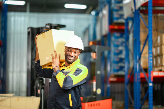 Man placing a package on a shelf in a warehouse. He wears a safety vest and focuses on stocking goods properly.