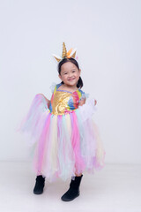 Young girl beams with joy while holding out her sparkly pastel unicorn dress doing a curtsy, full of whimsical colors and playful energy. Isolated on a light background.