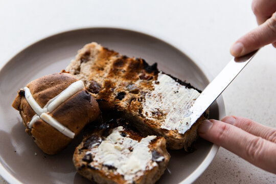 toasted hot cross buns getting buttered
