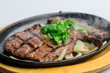 Sizzling Grilled Beef Steak with Fresh Cilantro on Hot Plate