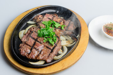 Sizzling Grilled Beef Steak with Fresh Cilantro on Hot Plate