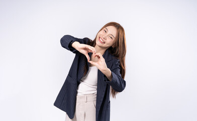 Fototapeta premium Beautiful woman making hand gesture with heart shape smiling face in suit photoshoot in studio on white background