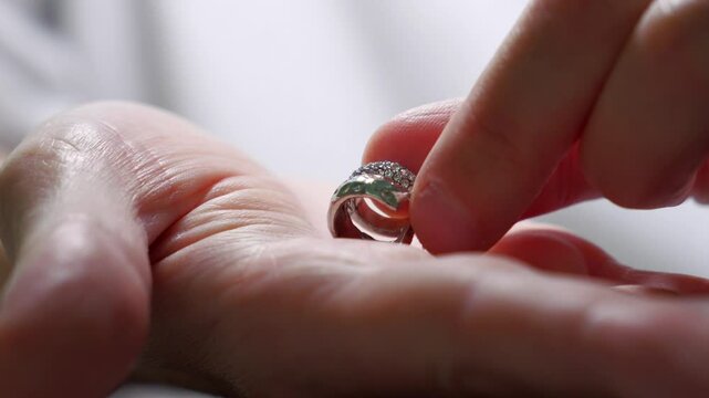 Silver jewelry in a man's hands.
Silver jewelry with precious stones shines on a man's hand.
A man holds a luxurious piece of jewelry in his hands
