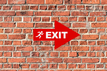 Fototapeta premium Red exit sign pointing to the right on brick wall