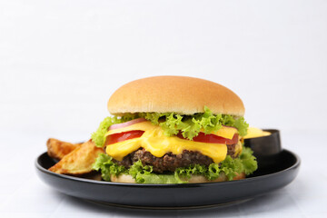 Tasty cheeseburger with sauce and potato wedges on white table, closeup