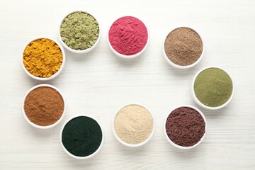 Frame of different superfood powders on white wooden table, flat lay. Space for text
