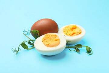 Boiled eggs and microgreens on light blue background, closeup