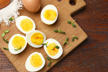 Halves of hard boiled eggs with microgreens on wooden table, top view