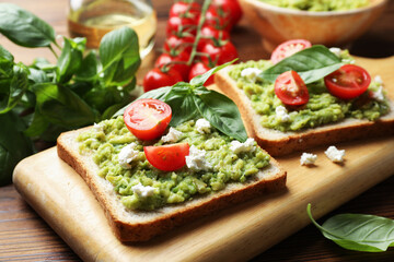 Delicious sandwiches with avocado, tomatoes, basil and cheese on table, closeup