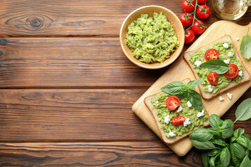 Delicious sandwiches with avocado, tomatoes, basil and cheese on wooden table, flat lay. Space for text