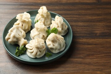 Delicious khinkali with cilantro on wooden table, closeup. Space for text