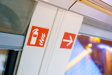 Orange Fire Extinguisher and Arrow Signage on a Train's White Door Indicates Emergency Equipment...