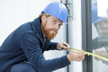 young engineer with safety helmet measuring window
