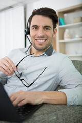 suave man sat on sofa using headset and laptop computer
