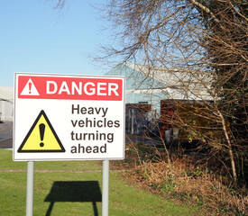 a warning sign for danger heavy vehicles turning ahead