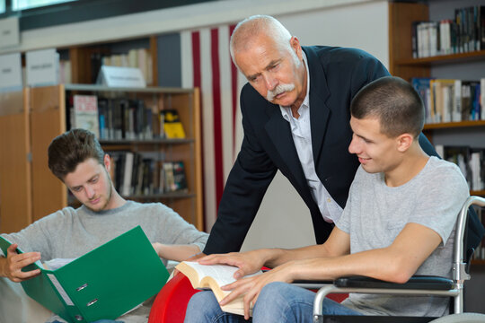 teacher helping students in library one in wheelchair