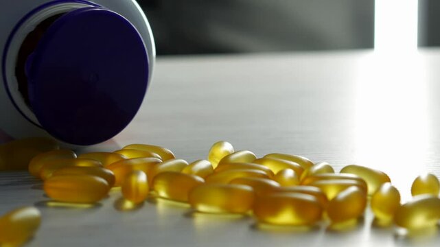 Omega 3 capsules in plan lie on a white table.
Scattered tablets on the table.
Gold vitamins with fish oil on the surface.
Healthy food.
Diet, nutrition, omega, natural, fish