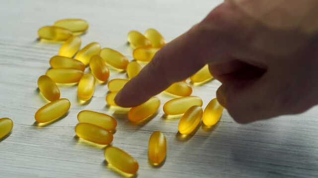 Omega 3 capsules in plan lie on a white table.
Scattered tablets on the table.
Gold vitamins with fish oil on the surface.
Healthy food.
Diet, nutrition, omega, natural, fish