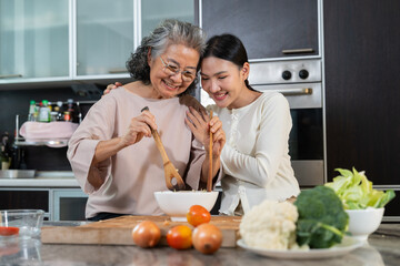 In the kitchen, a daughter and her elderly mother share a special bonding moment through cooking. Their care reflects family values, showcasing the role of a caregiver in retirement lifestyles
