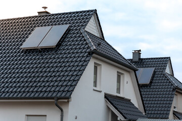 Modern house showing photovoltaic solar panels installed on dark tile roofs for renewable energy generation represents sustainable and environmentally friendly lifestyle choices