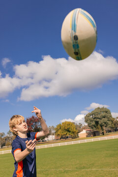 Junior rugby league player practicing ball pass on field