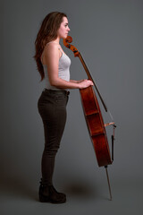 Studio portrait of young woman musician holding cello instrument