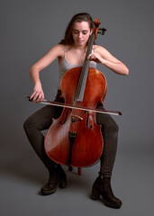 Young musician playing cello with passion and skill on gray background