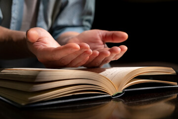 Hands reaching out from an open book while deep in thought during a quiet indoor moment