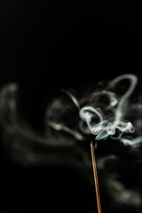 Burning incense with smoke on a black background.