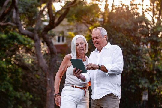 Senior couple holding and looking on a tablet outdoors