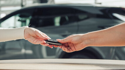 In a modern car dealership, the car salesman hands the keys to the buyer. The concept of a moment of trust and significance, emphasizing the importance of choosing the right car.