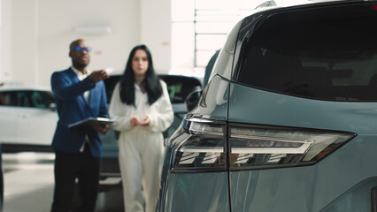 A customer at a car dealership consults with a salesperson, choosing a new vehicle. Concept: a...