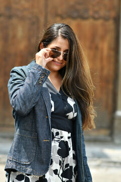 Mujer viajera colocando sus lentes de sol, chica joven y bella, con cabello largo y linda sonrisa. Toma Vertical.