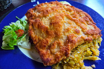 Crispy Breaded Schnitzel with Fresh Salad on Blue Plate for Culinary Presentation