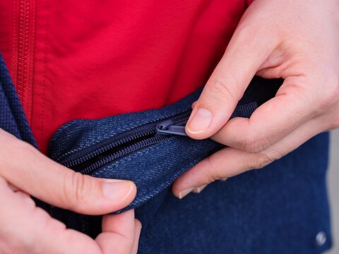 Woman pulling up the zip to open her denim bag.