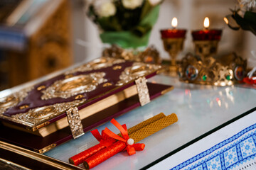 Orthodox Wedding Ceremony: Intricate Gospel Book and Lit Candles on Altar with Red Ribbons, Golden Details, Religious Ritual.