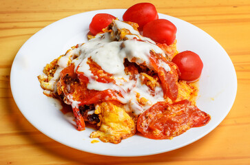 Homemade fried eggs with tomatoes and mayonnaise on white plate