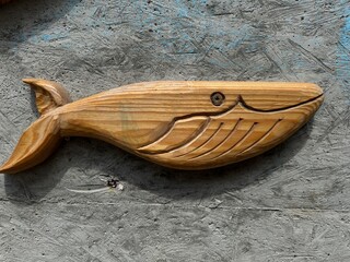 . Wooden spoon with carved whale tail design on textured background