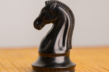 Black chess knight on a wooden table, close-up © Mariia