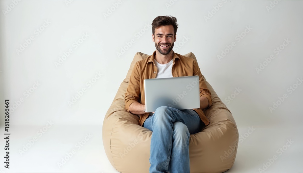 Poster young man sits bean bag chair using laptop computer. happy smiling guy works with notebook at home o