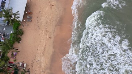 Aerial top-down drone video of ocean waves crashing gently onto a sandy beach in Phu Quoc, Vietnam. The footage features a soothing pattern of foam, wet sand, and natural textures, perfect for backgro - Powered by Adobe