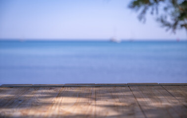 Summer vacation themed background - wooden table with sea in the background © LaSu
