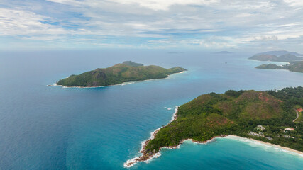 Aerial drone of lush green islands surrounded by vibrant turquoise waters, fading into the endless horizon. Praslin, Seychelles.
