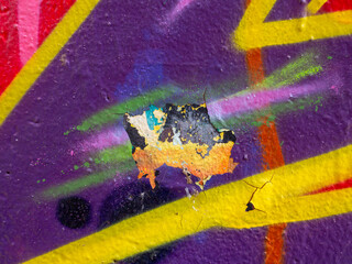 Detail of colorful graffiti wall. Old weathered colorful graffiti painted peeled plaster wall with falling off flakes of paint