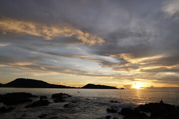 Serene Sunset Over Tranquil Ocean with Dramatic Clouds and Silhouette of Distant Islands