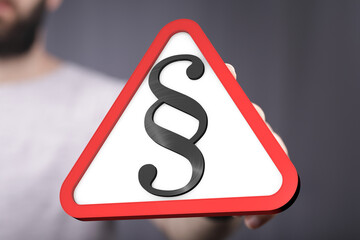 Hand holding a red triangle warning sign with a paragraph symbol.  Legal, law, warning concept.