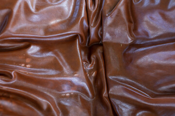 The brown leather of the sofa was wrinkled and shiny.