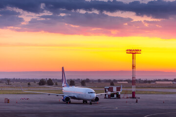Sunset view of airplane at the airport against colorful sky. Travel concept